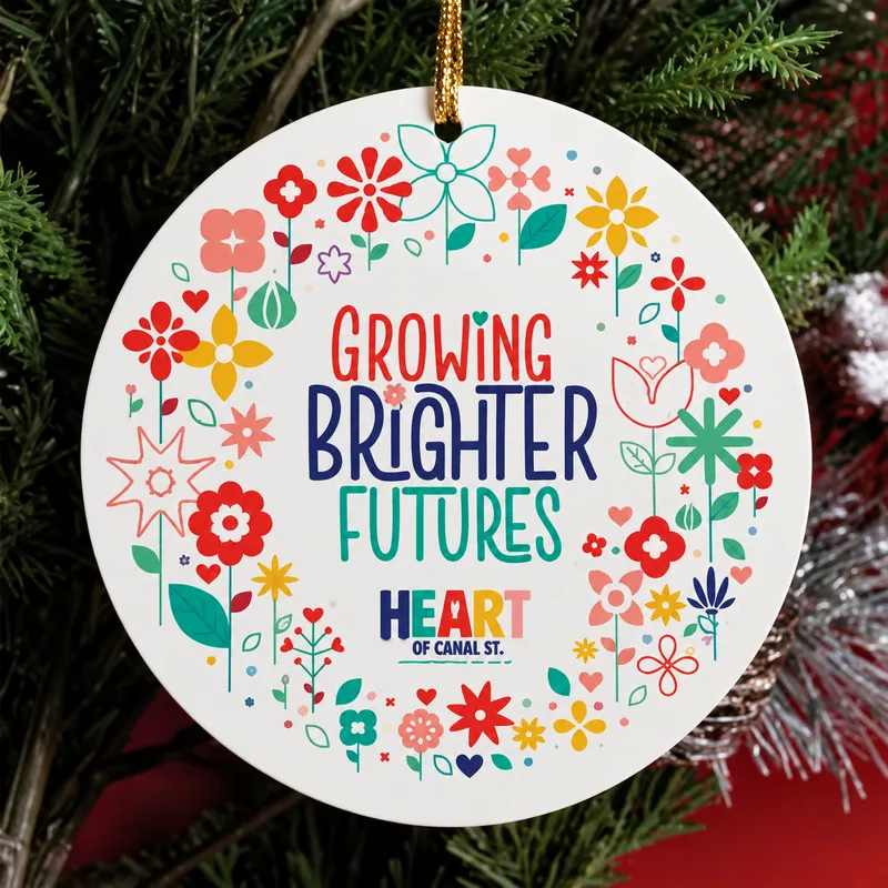 Round ceramic ornament with the Growing Brighter Futures wreath, hanging on a tree